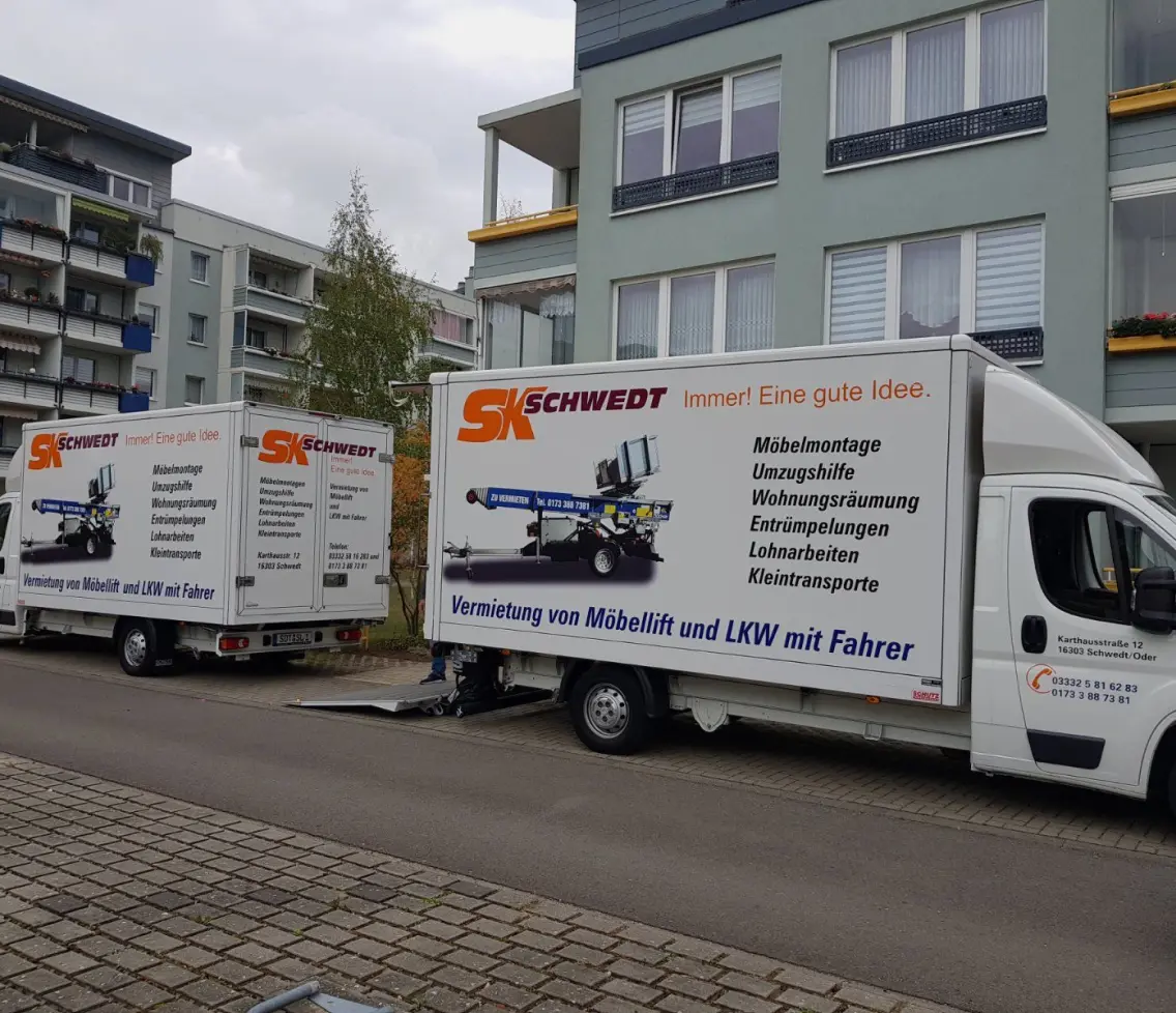 Zwei SK Schwedt Umzugsfahrzeuge mit Möbellift vor einem Wohnhaus